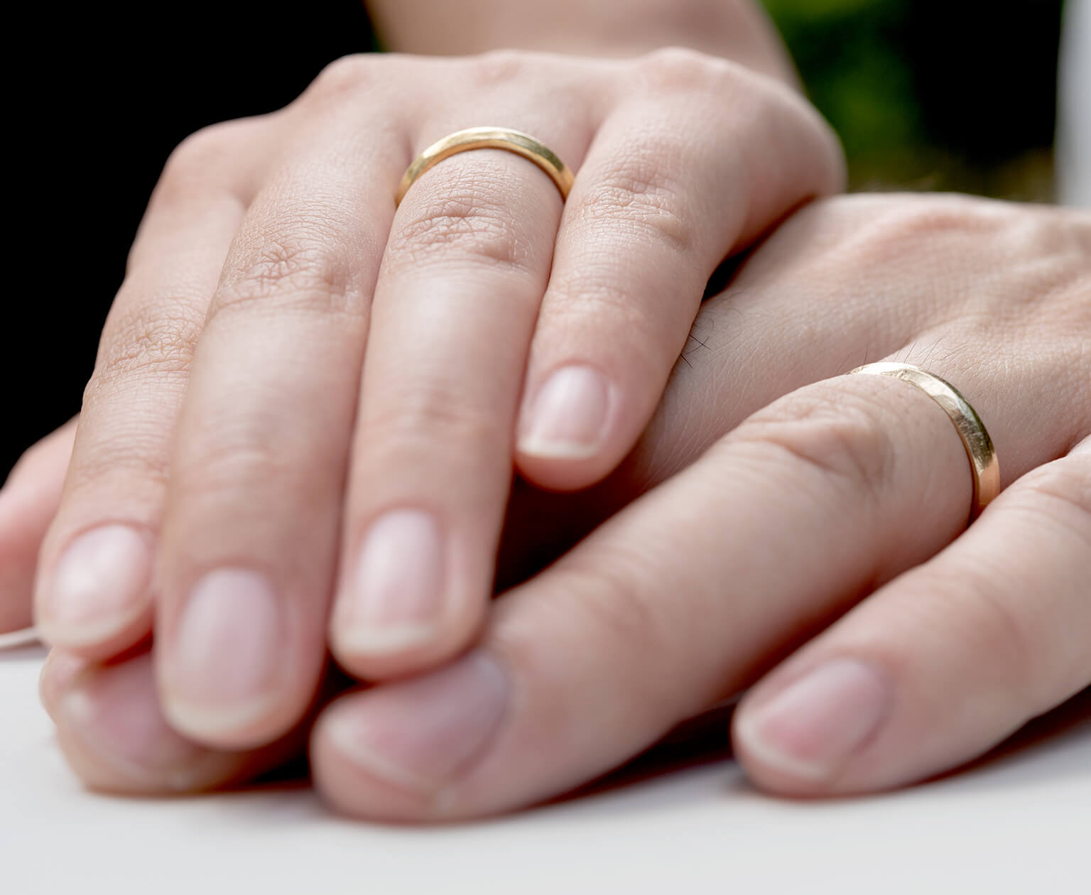 指輪をはめた重なり合う二人の手の写真